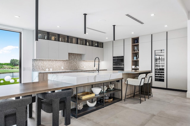 kitchen featuring a breakfast bar, sink, light tile patterned floors, and white cabinets