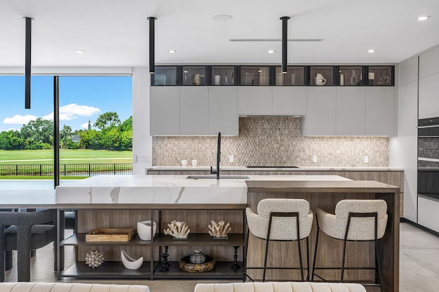 kitchen with sink, gas stovetop, tasteful backsplash, and a breakfast bar