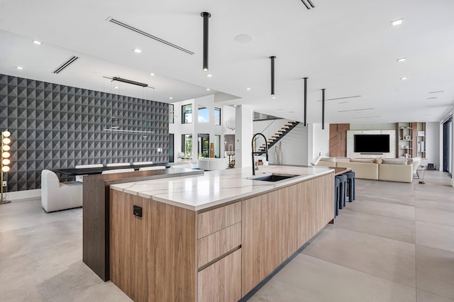 kitchen featuring sink, light stone counters, and a large island