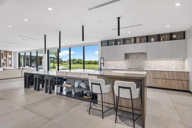 kitchen with sink, white cabinets, a center island with sink, and light tile patterned floors