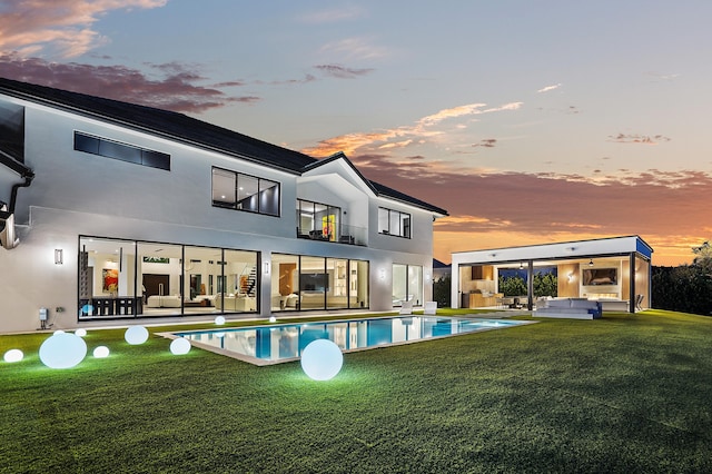 back house at dusk featuring a patio area and a yard