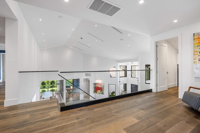 hallway with wood-type flooring and vaulted ceiling