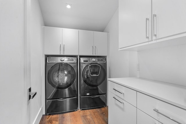 laundry area with cabinets, dark hardwood / wood-style flooring, and washing machine and dryer