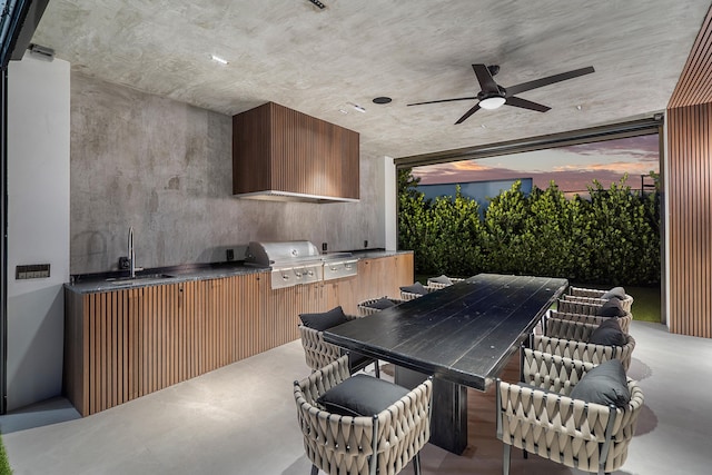 patio terrace at dusk with an outdoor kitchen, area for grilling, sink, and ceiling fan