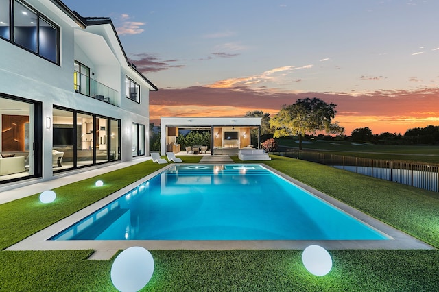 pool at dusk featuring a patio and a yard