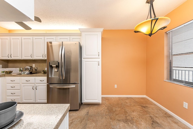 kitchen featuring pendant lighting, light tile patterned floors, white cabinets, and stainless steel refrigerator with ice dispenser