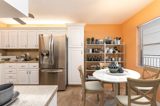 kitchen featuring white cabinetry, light tile patterned flooring, and stainless steel refrigerator with ice dispenser