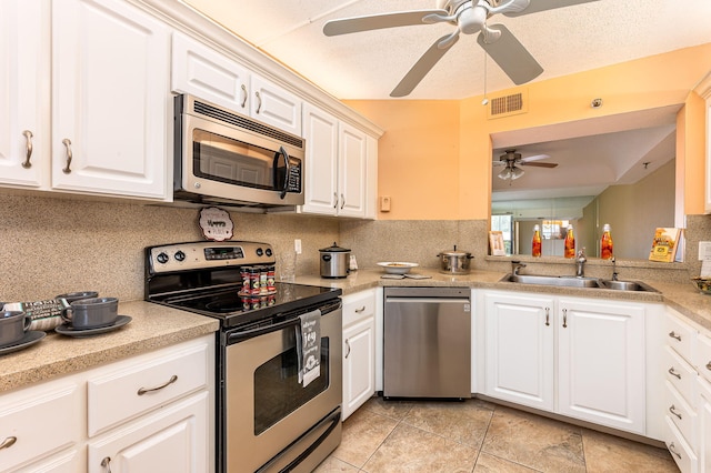 kitchen with appliances with stainless steel finishes, white cabinetry, backsplash, and ceiling fan