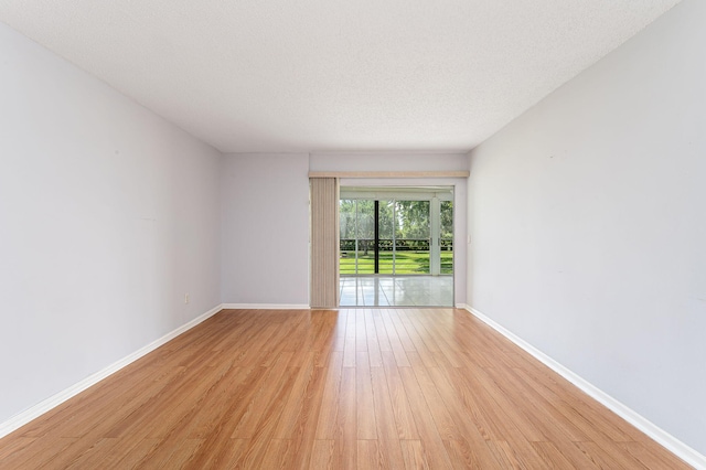 spare room with a textured ceiling and light hardwood / wood-style flooring