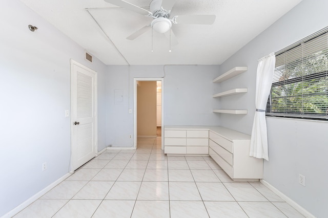 unfurnished bedroom with light tile patterned floors, ceiling fan, and a closet