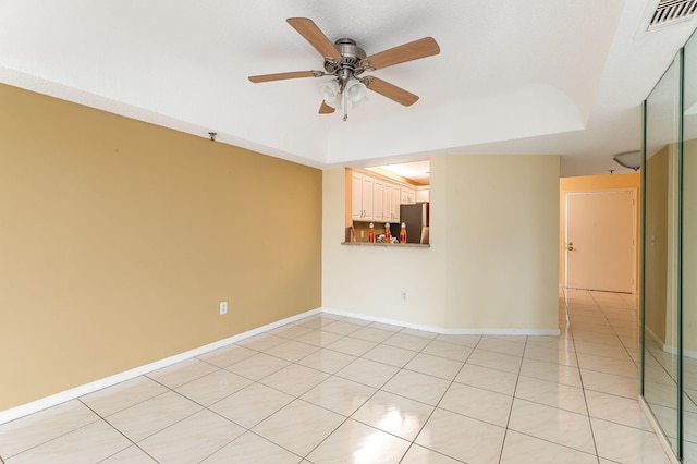 tiled spare room with a tray ceiling and ceiling fan