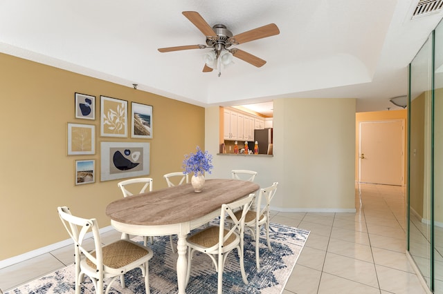 tiled dining area with a tray ceiling and ceiling fan