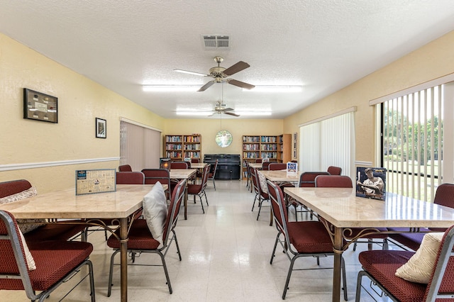 tiled dining area with ceiling fan and a textured ceiling