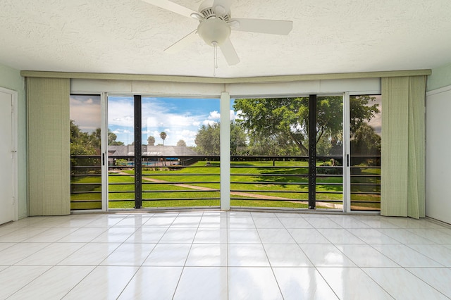 unfurnished room with a textured ceiling, ceiling fan, and light tile patterned floors