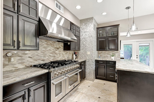 kitchen featuring light stone counters, tasteful backsplash, wall chimney exhaust hood, pendant lighting, and double oven range