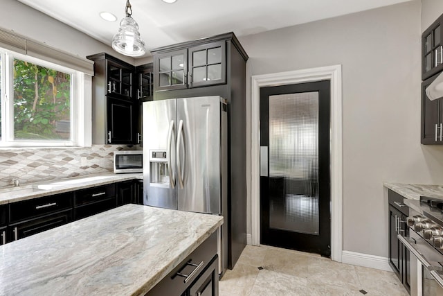 kitchen with pendant lighting, stainless steel appliances, light stone countertops, and decorative backsplash