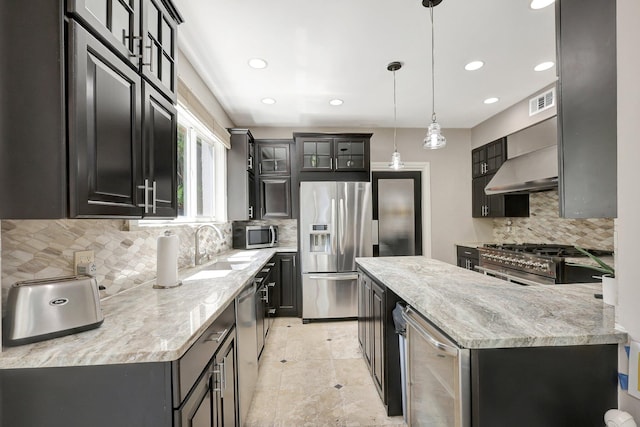 kitchen featuring sink, hanging light fixtures, backsplash, appliances with stainless steel finishes, and light stone countertops