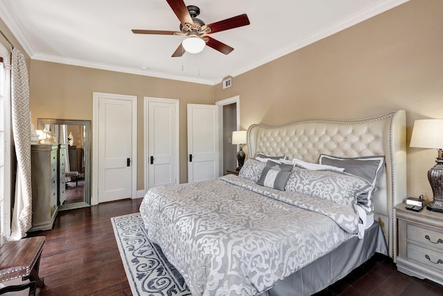 bedroom featuring crown molding, dark hardwood / wood-style floors, ceiling fan, and multiple closets