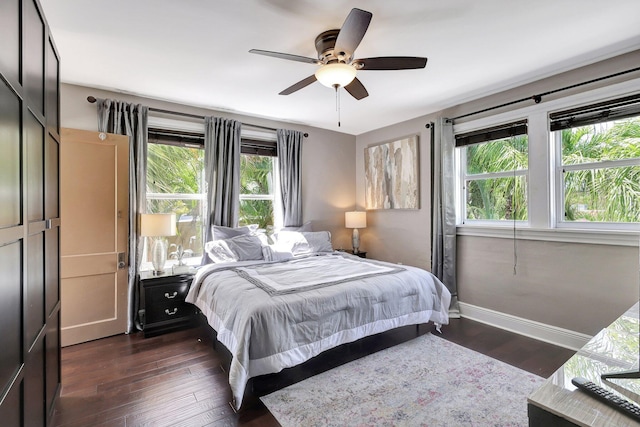 bedroom featuring ceiling fan, dark wood-type flooring, and multiple windows