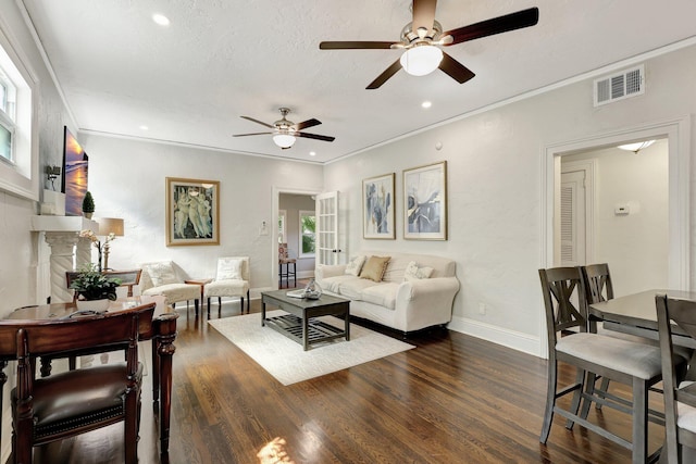 living room featuring ceiling fan, a textured ceiling, a premium fireplace, dark wood-type flooring, and crown molding