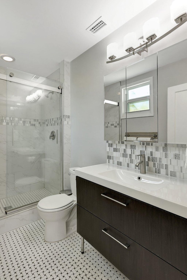 bathroom with decorative backsplash, a shower with door, vanity, and toilet