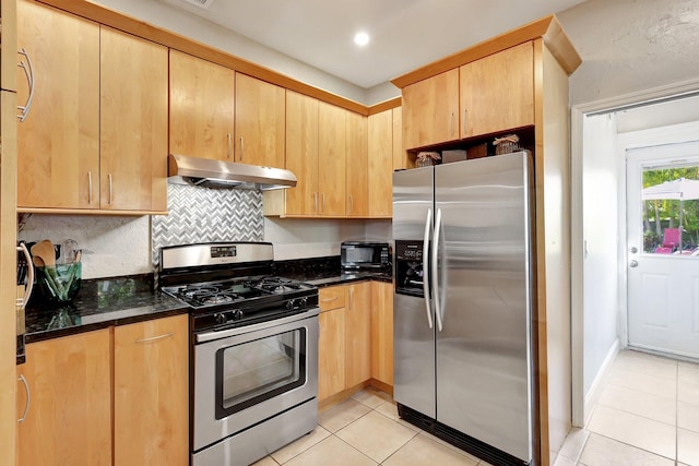 kitchen with light brown cabinets, light tile patterned floors, tasteful backsplash, appliances with stainless steel finishes, and dark stone counters