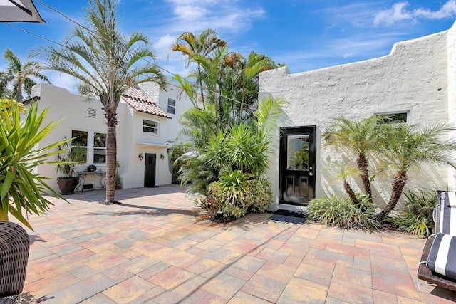 view of exterior entry with a patio area