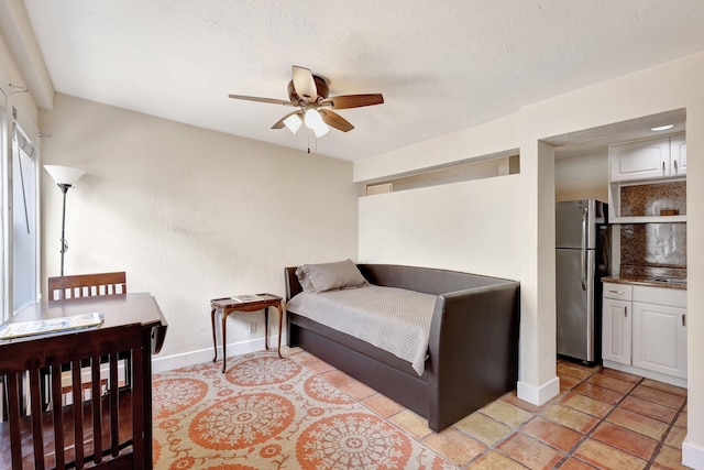 bedroom featuring a textured ceiling, stainless steel refrigerator, and ceiling fan