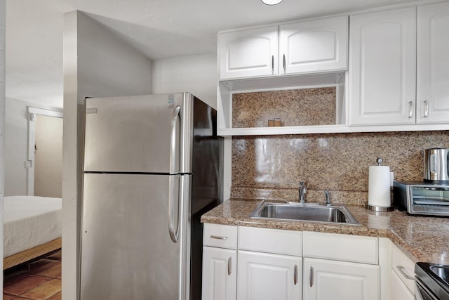 kitchen with appliances with stainless steel finishes, backsplash, white cabinetry, and sink