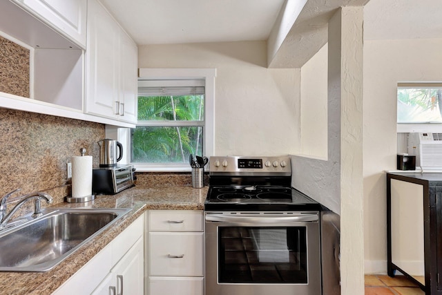 kitchen with plenty of natural light, stainless steel electric range, white cabinetry, and sink