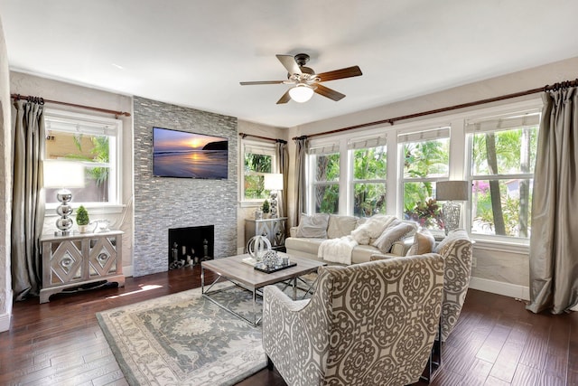 living room with ceiling fan, a stone fireplace, and dark hardwood / wood-style flooring