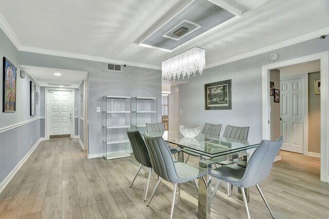 dining area featuring light hardwood / wood-style flooring, a notable chandelier, and ornamental molding