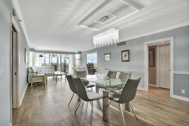 dining room with a chandelier, light wood-type flooring, and ornamental molding