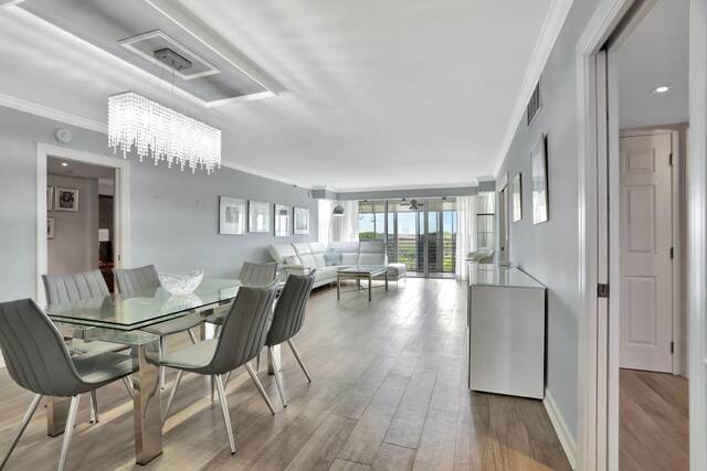 dining space with crown molding, a chandelier, and light hardwood / wood-style flooring