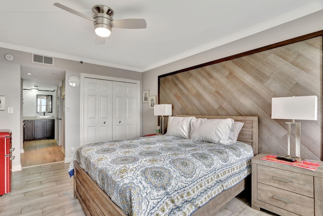 bedroom featuring a closet, ceiling fan, light wood-type flooring, ornamental molding, and sink