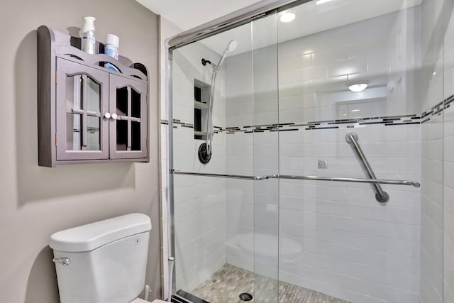 bathroom featuring a shower with shower door and toilet