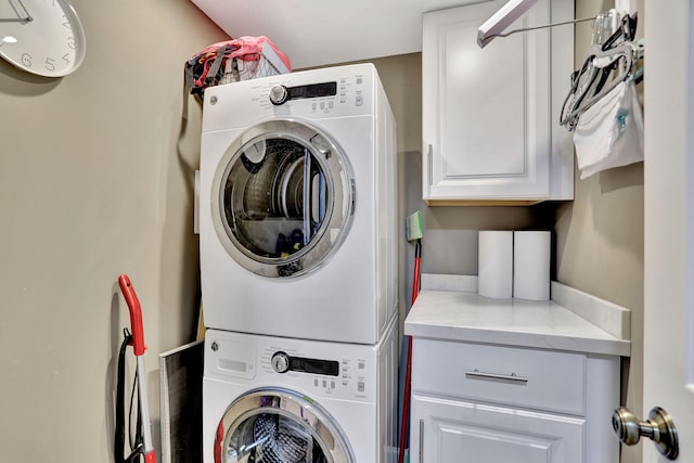 washroom with stacked washing maching and dryer and cabinets