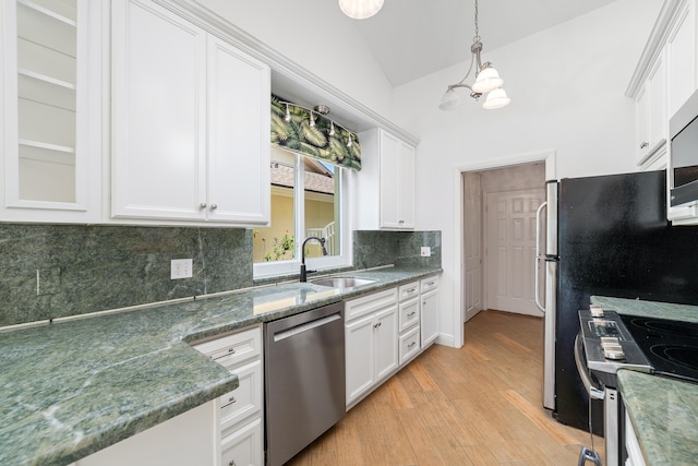 kitchen with vaulted ceiling, appliances with stainless steel finishes, light wood-type flooring, and backsplash