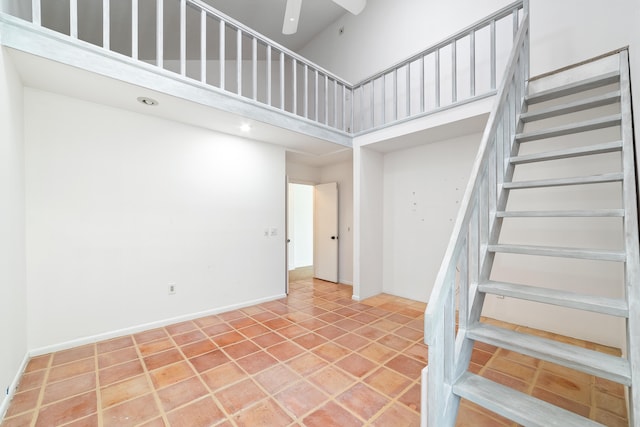 staircase with ceiling fan, tile patterned flooring, and a high ceiling