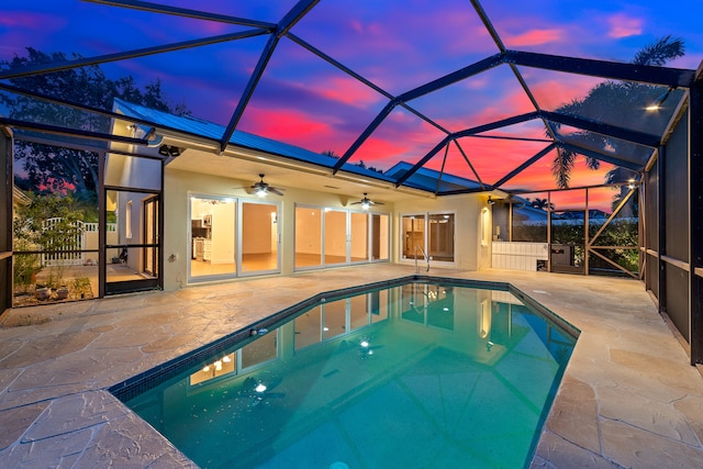 pool at dusk featuring ceiling fan, a patio, and a lanai