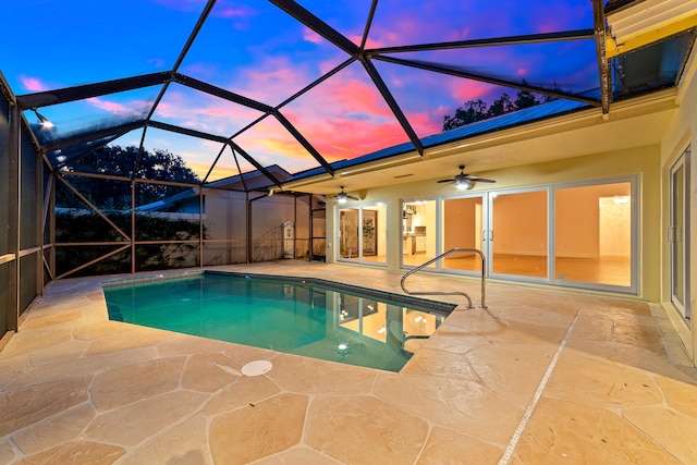 pool at dusk featuring ceiling fan, a patio, and glass enclosure