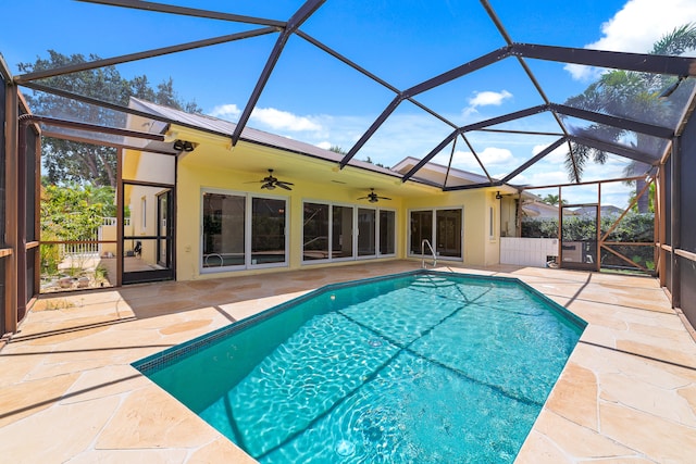 view of swimming pool with ceiling fan, glass enclosure, and a patio area