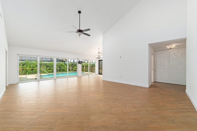 unfurnished living room featuring high vaulted ceiling, light hardwood / wood-style flooring, and ceiling fan with notable chandelier