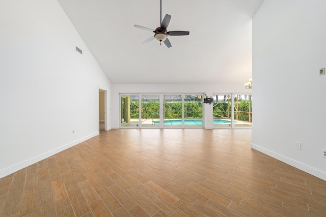 unfurnished living room with high vaulted ceiling, light hardwood / wood-style flooring, and ceiling fan with notable chandelier