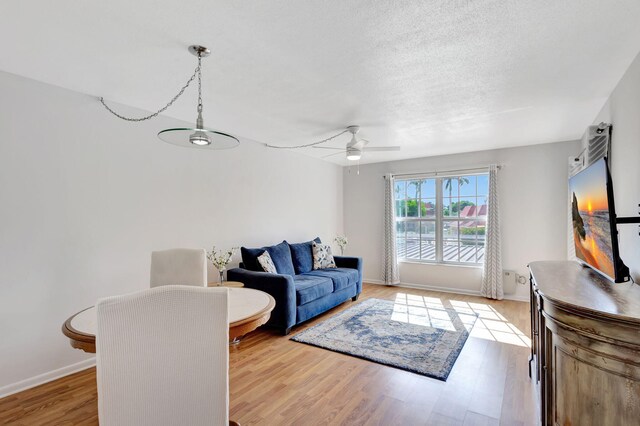 living room with a textured ceiling, light hardwood / wood-style floors, and ceiling fan