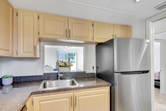 kitchen featuring ceiling fan, light brown cabinets, sink, and stainless steel fridge