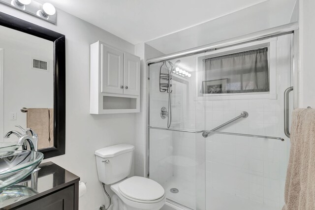 bathroom featuring vanity, toilet, and a shower with door