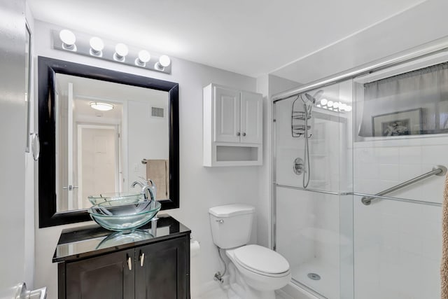 bathroom featuring vanity, toilet, and a shower with door