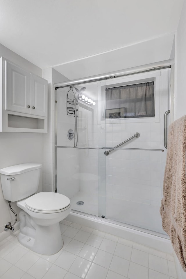 bathroom with a shower with door, toilet, and tile patterned floors