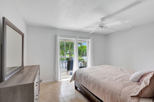 bedroom featuring ceiling fan, light tile patterned flooring, access to exterior, and a textured ceiling